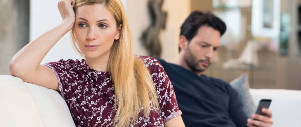Couple sitting on couch looking unhappy